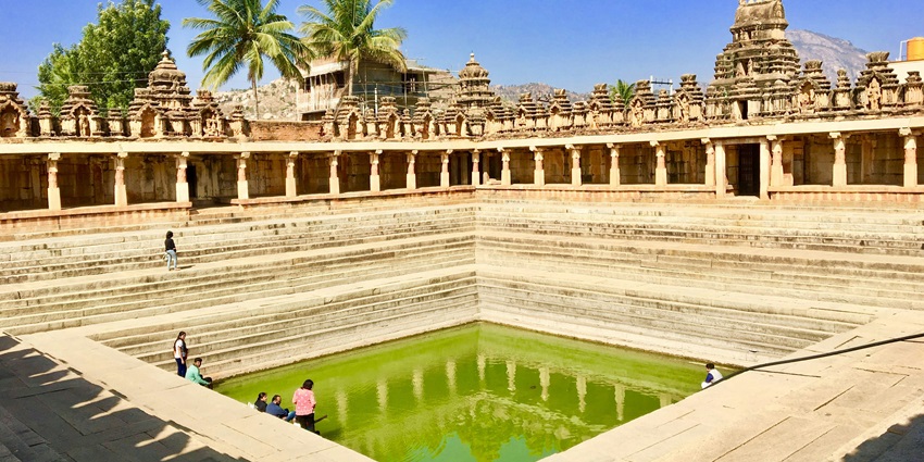 A serene lake inside the temple courtyard with devotees all around it