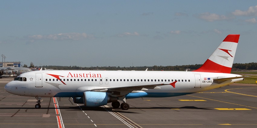 White and red Airbus A320 commercial aeroplane parked on a runway with other aeroplanes