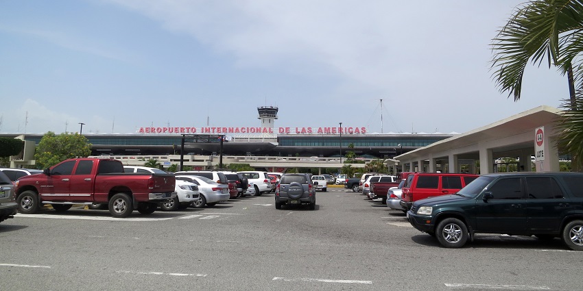 Panorama of parked cars and the main entryway of Las Américas International Airport.