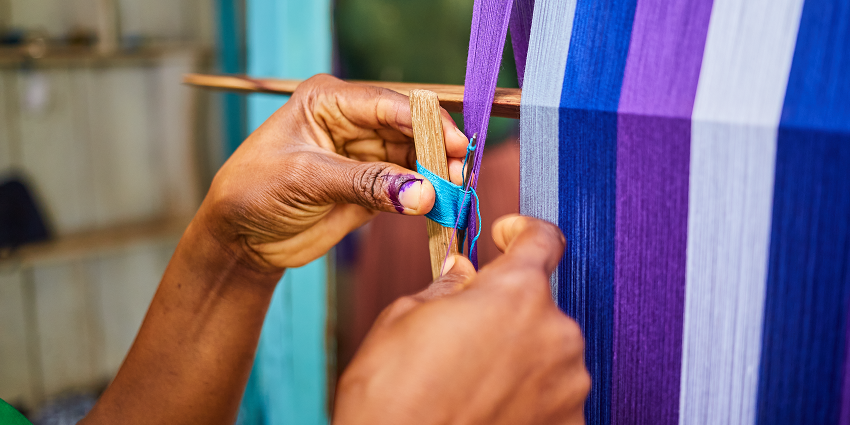 An image of a weaving loom, colourful threads arranged in a pattern, representing the weaving experience