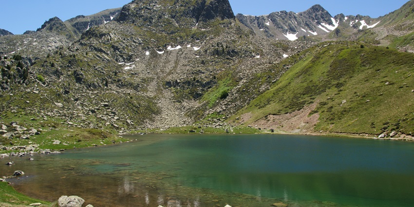 The Les Abelletes Lake surrounded by mountains makes for a great place for family picnics near El Pasa de la Casa.