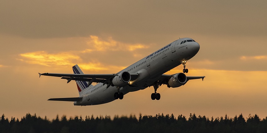Airplane taking off at sunset with a forested landscape at one of the airports in Czech Republic.