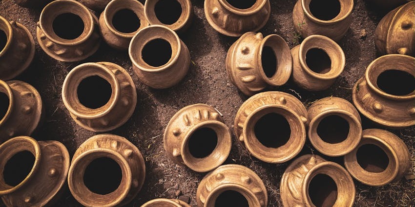 Handcrafted clay pots with textured designs arranged on the ground in a traditional market