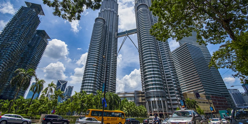 Petronas Twin Towers, Kuala Lumpur standing against a blue sky, surrounded by city life