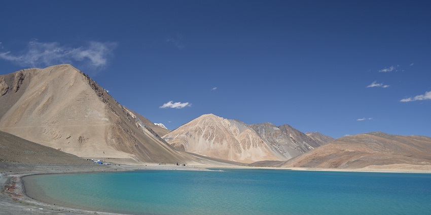 Pangong Tso lake with a large water body surrounded by sandy shorelines and mountains