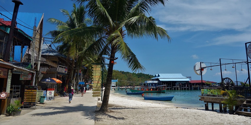 An image showing a beach with coconut trees on Koh Rong island and Cambodia's blue sea waters