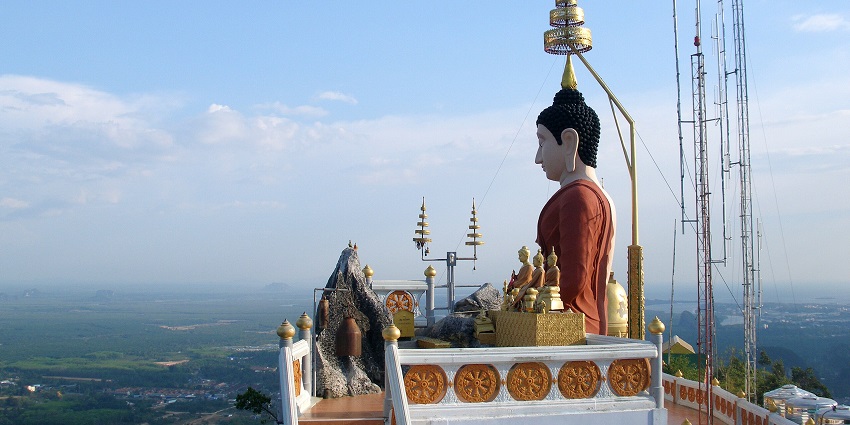Tiger Cave Temple in Krabi surrounded by lush forests and towering limestone cliffs.