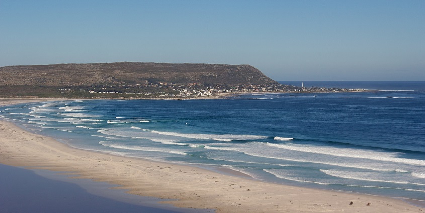 A top view of Noordhoek Beach, showing its white sand and clear blue water.