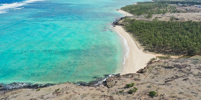 A picture of Pont Naturel, Mauritius, with turquoise ocean and cliffs in the background.