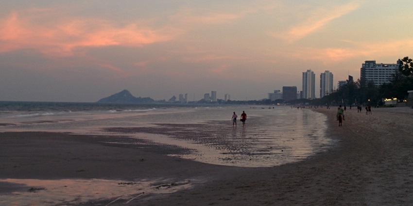 View of Hua Hin public beach with visitors, shoreline, and surrounding coastal area.