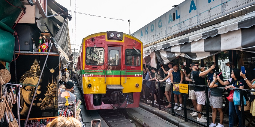 A picture of the market with a train passing through the market stalls.