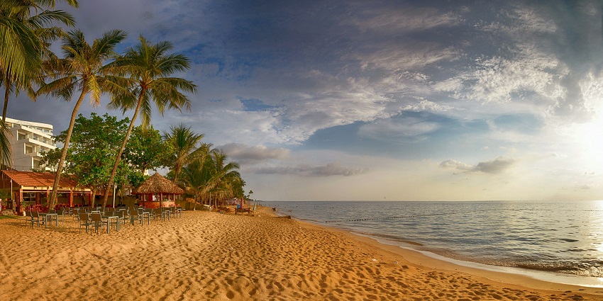 A view of a beach in Vietnam with sandy shores, azure waters and lush green meadows.