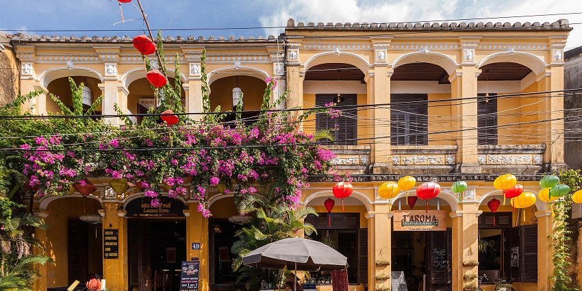 A charming yellow colonial-style building adorned with vibrant lanterns and bougainvillaea