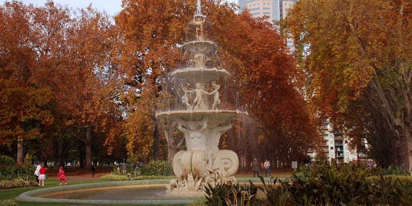 View of Carlton Gardens in Melbourne, featuring lush trees, open lawns, and pathways.