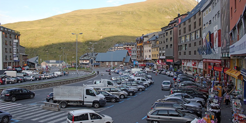 The streets of El Pasa de la Casa lined up with vehicles with mountains in the backdrop.