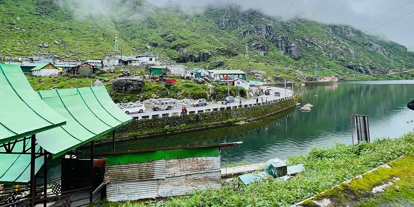 Changu Lake with a still water body surrounded by sandy shorelines and grey clouds.