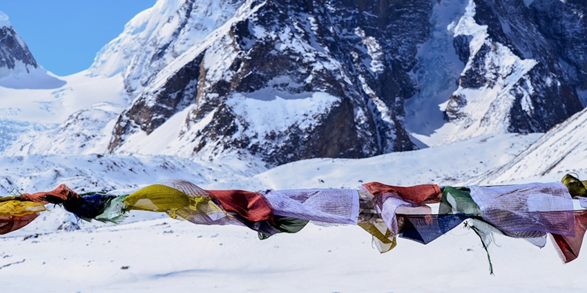 An image of Gurudongmar Lake in December with snowy mountains and a blue sky.