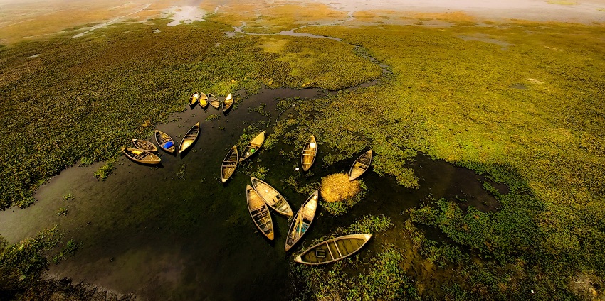 Kanwar Lake from above with several boats on the water body surrounded by greenery