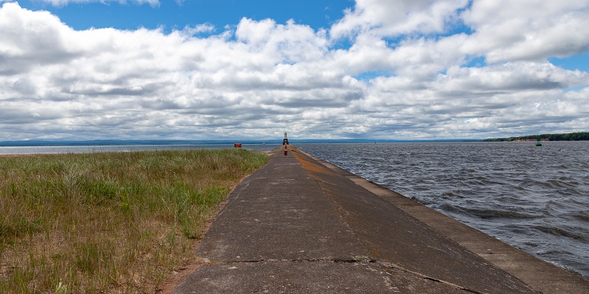 Keweenaw waterway at Torch Lake with a large water body, concrete shoreline and grass.