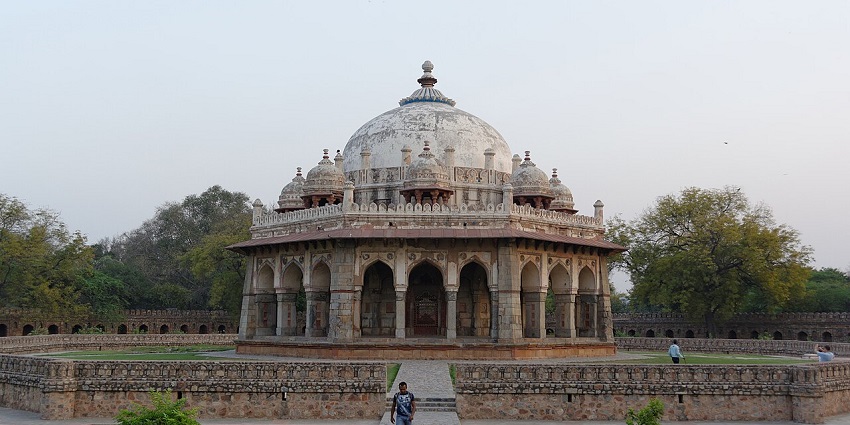 A beautiful mosque stands tall in a serene landscape, surrounded by lush greenery under a clear blue sky.