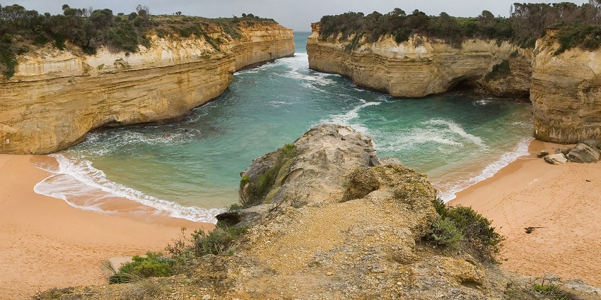 A picturesque view of Loch Ard Gorge’s turquoise waters and towering cliffs.