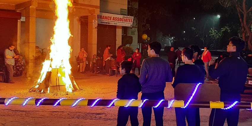 An image of people sitting around the bonfire, celebrating the famous crop festivals in India.