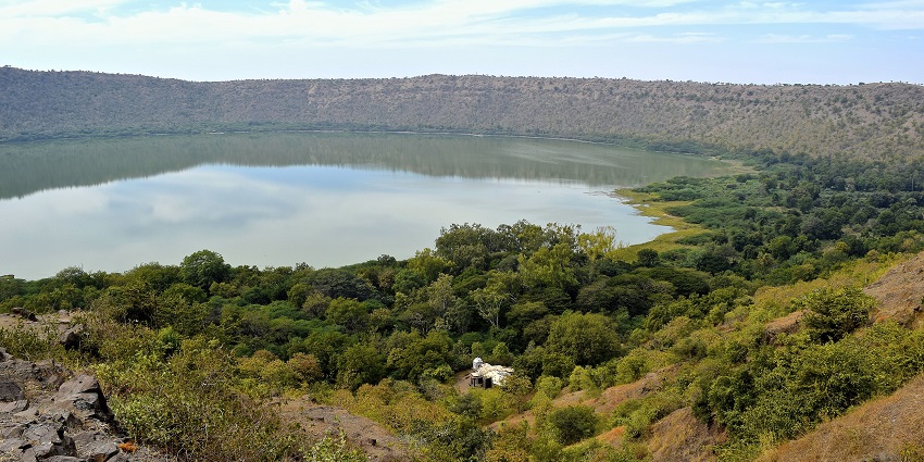 Lonar crater, a circular lake formation surrounded by greenery, and a small white structure