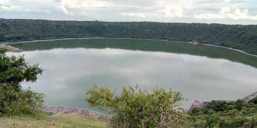 An image of Lonar Crater Lake, a lake in Maharashtra, with green waters surrounded by a meteorite crater.