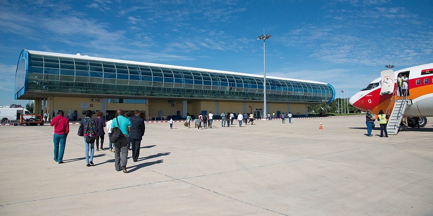 Lubango airport with a parked aeroplane and passengers coming out of the aeroplane.