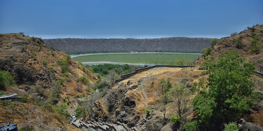 Lonar crater lake at a distance, surrounded by greenery, and stairs around the impact hills