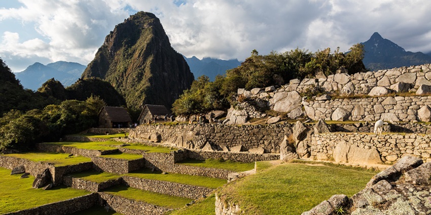 A picture of a lush green hill in Peru with rocky platforms and grassy expanses all around