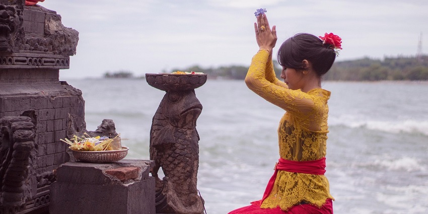 An image showing a woman performing rituals, representing a traditional festival in India.