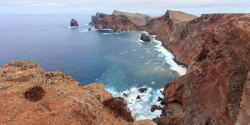 A majestic aerial view of a rocky shore with views of scenic blue ocean in Portugal
