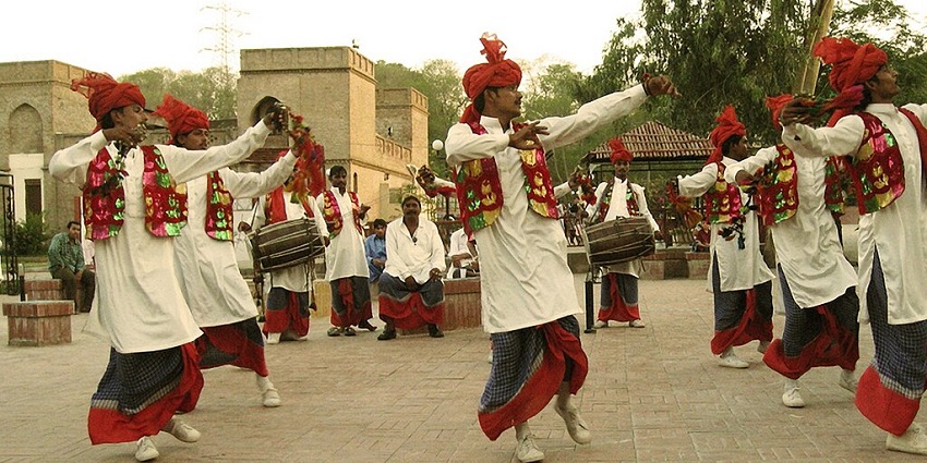 An image of a traditional bhangra dance performance with dancers in colorful attire and musicians playing drums