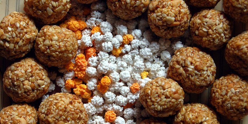An image of round sesame and peanut brittle balls surrounding colorful sugar-coated puffed rice balls, made during makar Sankranti