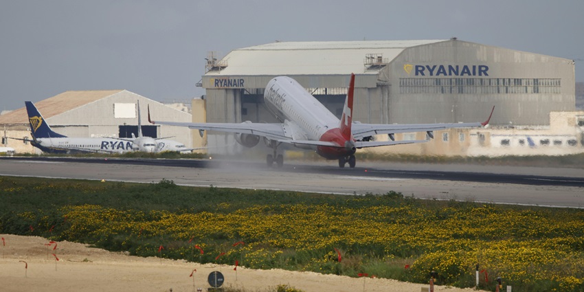 Big commercial aeroplane landing at an airport with multiple aeroplanes parked in the back