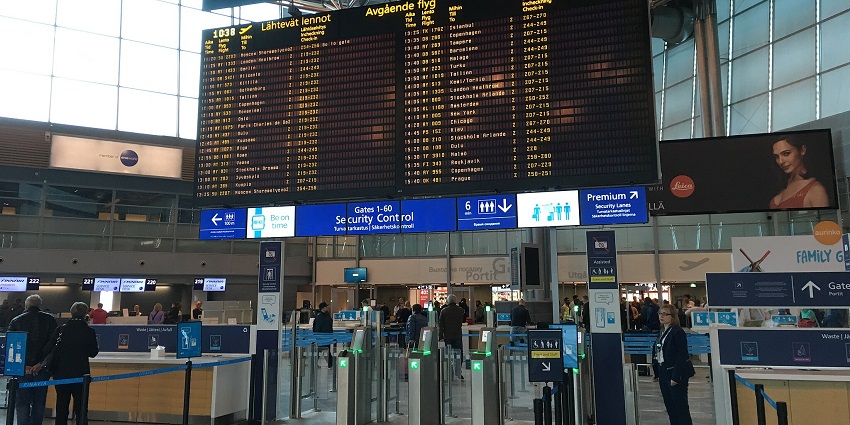 A flight information screen at Helsinki Airport shows arrivals and departures for different flights.