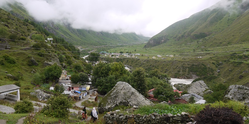 A view of a small village in the mountains, surrounded by green hills under blue sky