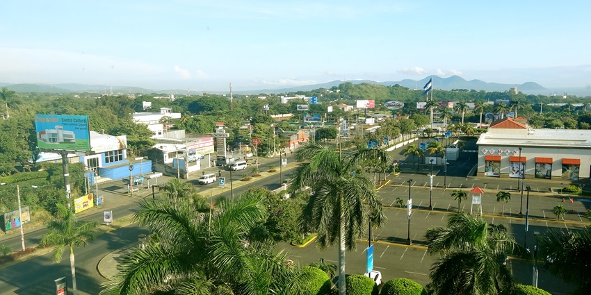 A panoramic view of Managua, Nicaragua, displaying buildings, trees, and a distant lake.