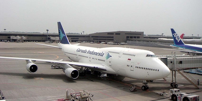 A white aeroplane awaits its passengers on the runway with a fleet of other flights.