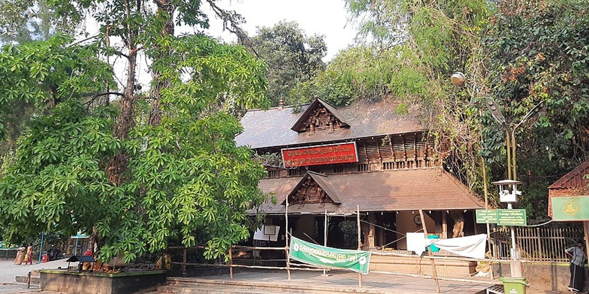 A traditional wooden temple building of Mannarasala Temple with intricate carvings.