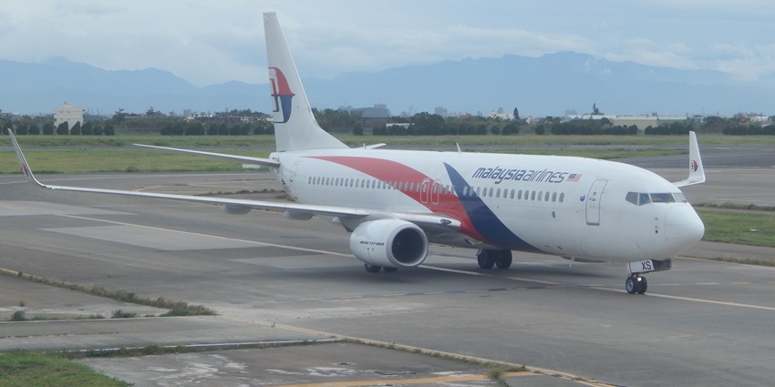 A Malaysian Airlines flight is getting ready for takeoff on a runway at an airport