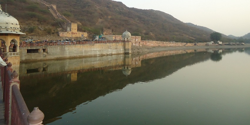 An image of Maota Lake, a lake in Jaipur, with calm waters reflecting the historic Amber Fort