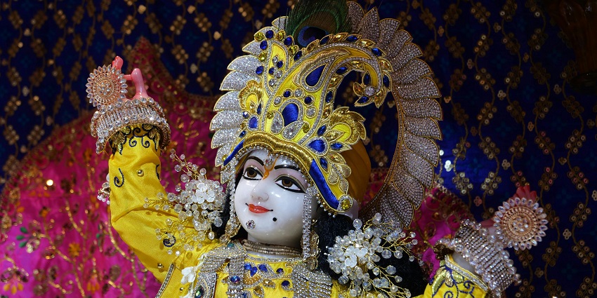 A beautifully adorned statue of the Hindu deity Krishna, with gold and jewel decorations