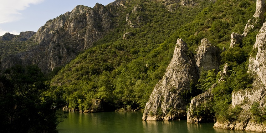Matka Canyon with steep cliffs, clear river, and lush greenery along the banks.