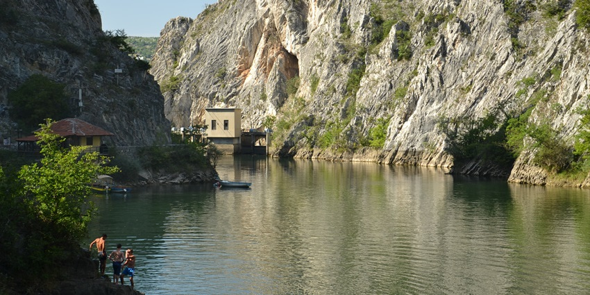 A picture of Matka Canyon, a must-see among places to visit in North Macedonia, and kayakers exploring the river.