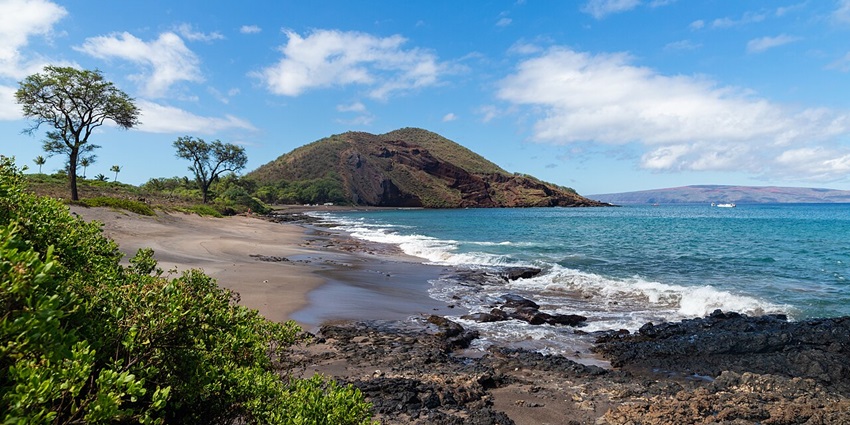 A view of Maui in Hawaii featuring majestic peaks, lush greenery, and azure waters.