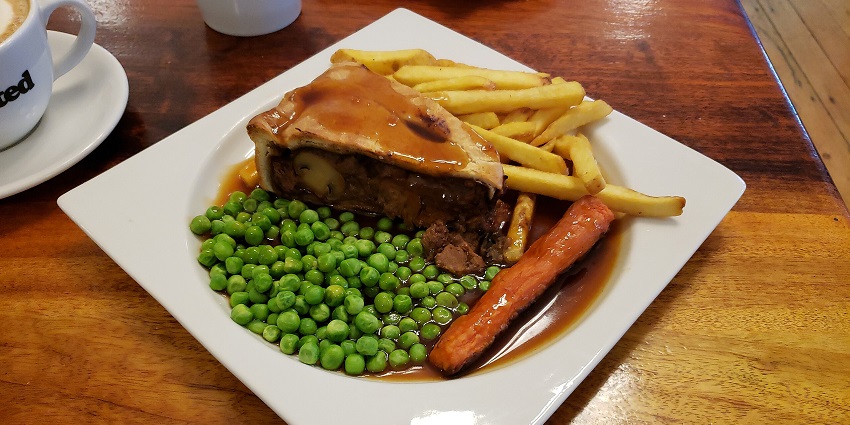 Meat pie of wine, beef and mushrooms served with green peas, French fries and curry
