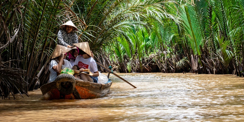 An image showing river life in Mekong Delta, Cai Be, Vietnam, with boats and local activity.