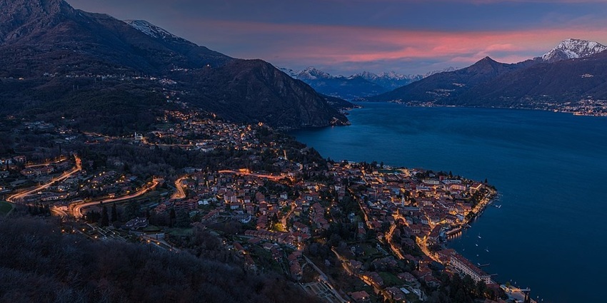 Menaggio at sunset on Lake Como, with warm light illuminating the town and the lake.